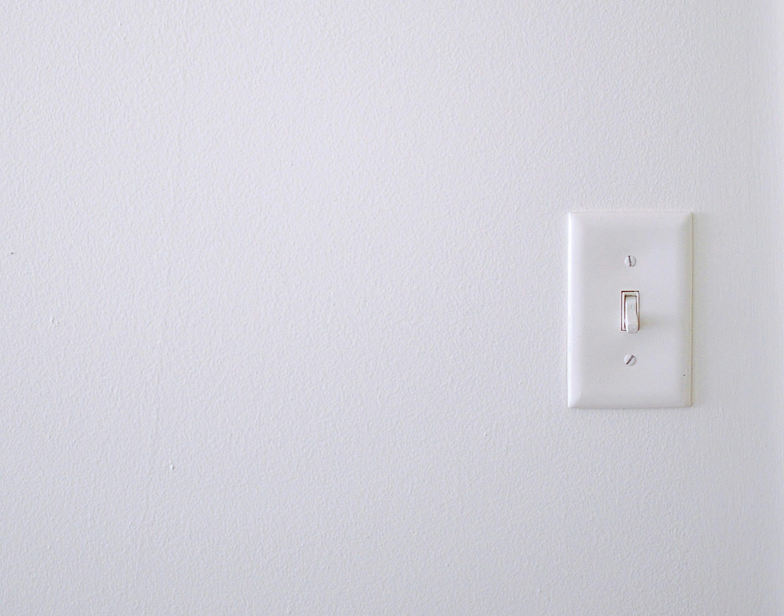 A white light switch on a white wall. Photo by Isabella Fischer on Unsplash.